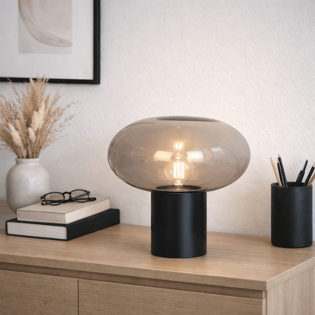 Alba 32cm Zwart/Rookkleurig tafellamp Van Nordic Lighting - De zwarte metalen voet zorgt voor een stabiele en elegante uitstraling, terwijl de kap van rookglas een zacht en sfeervol licht cre&euml;ert.