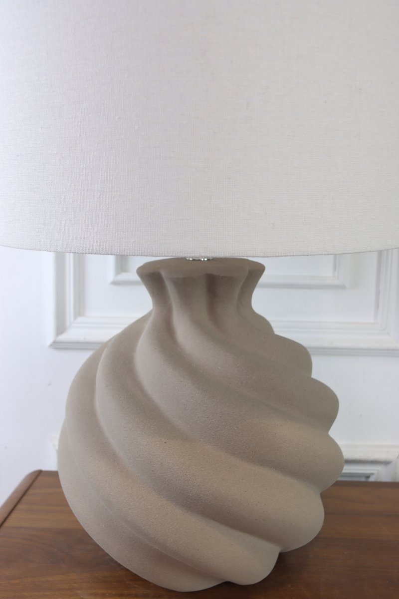 Vindel 52cm Zand tafellamp Van Lampan - De keramische lampvoet heeft een zandkleurig, gestructureerd oppervlak en een zacht, wervelend ontwerp dat een levendige en sculpturale uitstraling geeft.
