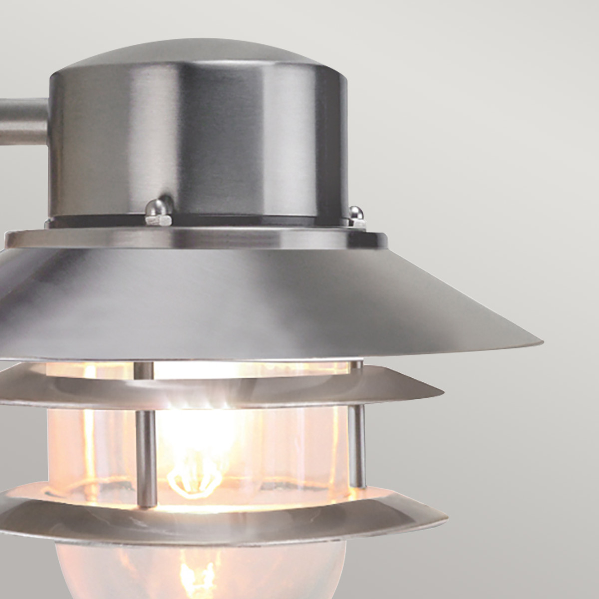 Copenhagen Ø22 Geborsteld staal buitenlamp Van Elstead Lighting - Tillverkad av rostfritt st&aring;l i borstad finish och glas, erbjuder den en h&aring;llbar och v&auml;dert&aring;lig konstruktion som passar perfekt f&ouml;r fasader, entr&eacute;er och uteplatser.