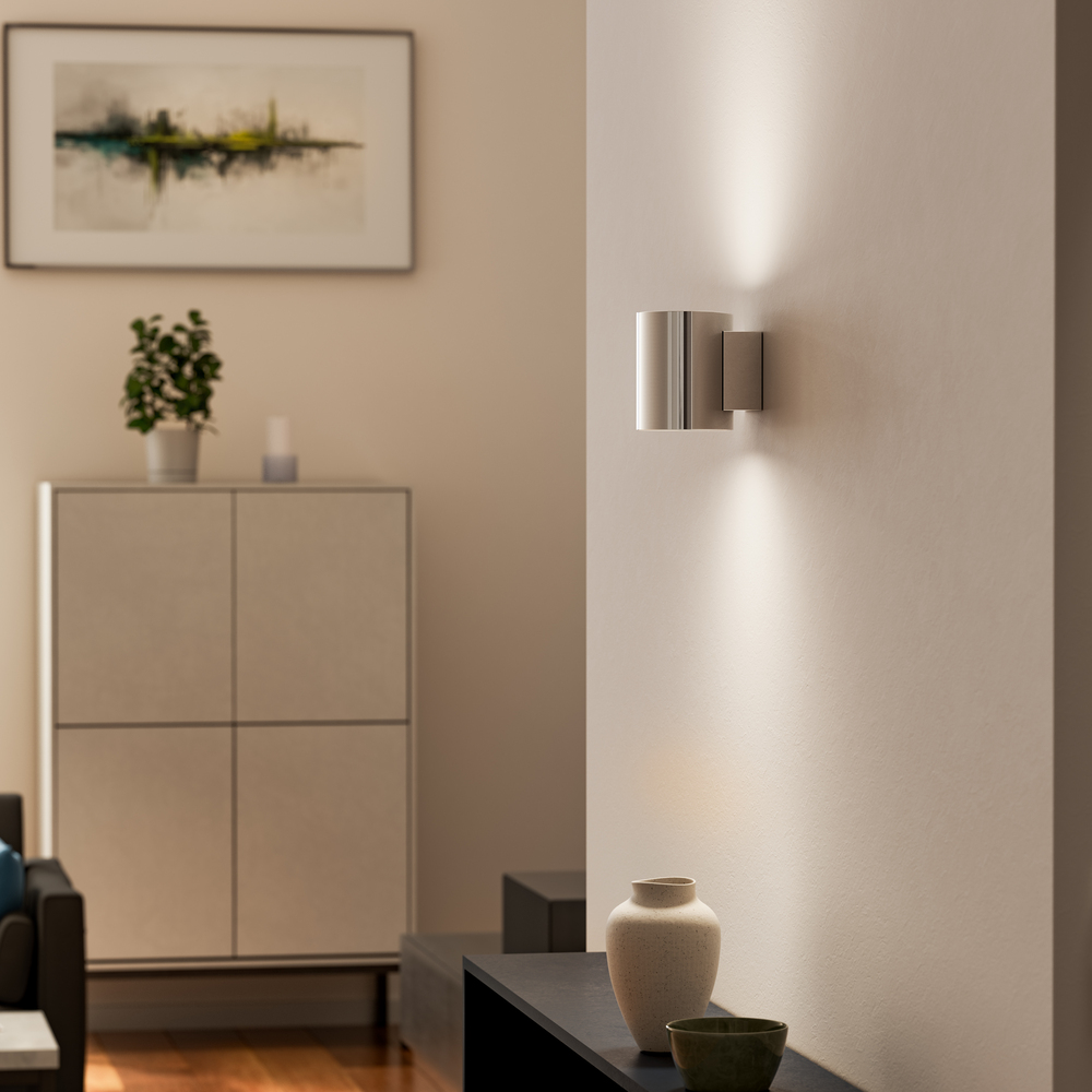 Evoke S Chroom wandlamp Van Herstal - Den smarta konstruktionen med b&aring;de upp- och nerljus g&ouml;r den till ett utm&auml;rkt val f&ouml;r att belysa din hall, vardagsrum eller sovrum p&aring; ett subtilt men effektfullt s&auml;tt.