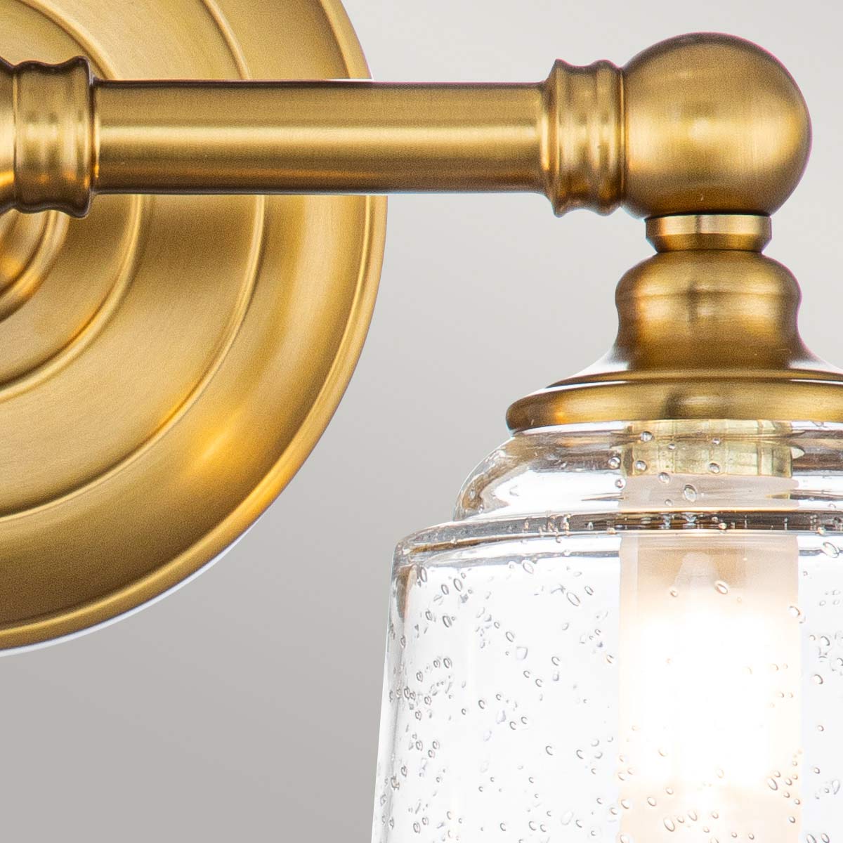 Huguenot Lake 33cm Messing badkamerlamp Van Elstead Lighting - De elegante ronde details en de met de hand gesneden monturen geven een gevoel van traditioneel vakmanschap, terwijl het heldere, gestructureerde glas een zacht en uitnodigend licht creëert.