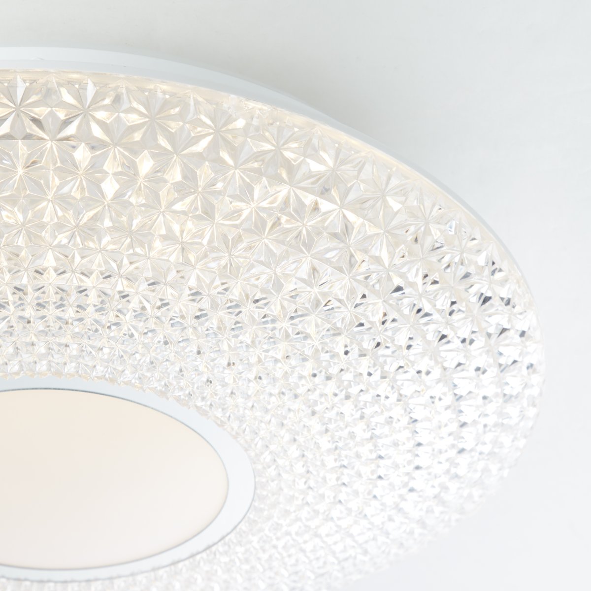 Lucian Ø40 Wit plafondlamp Van Brilliant - Het ledpaneel wordt omarmd door een helder scherm met kleine prisma's, wat een prachtig lichtpatroon in de kamer cre&euml;ert wanneer de lamp brandt.