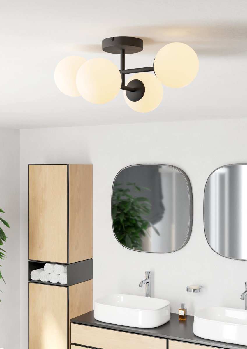 Castrivido 48cm Zwart badkamerlamp Van Eglo - De lamp is gemaakt van zwart metaal en heeft vier ronde, opalen glazen koepels die een zacht en gelijkmatig licht verspreiden.