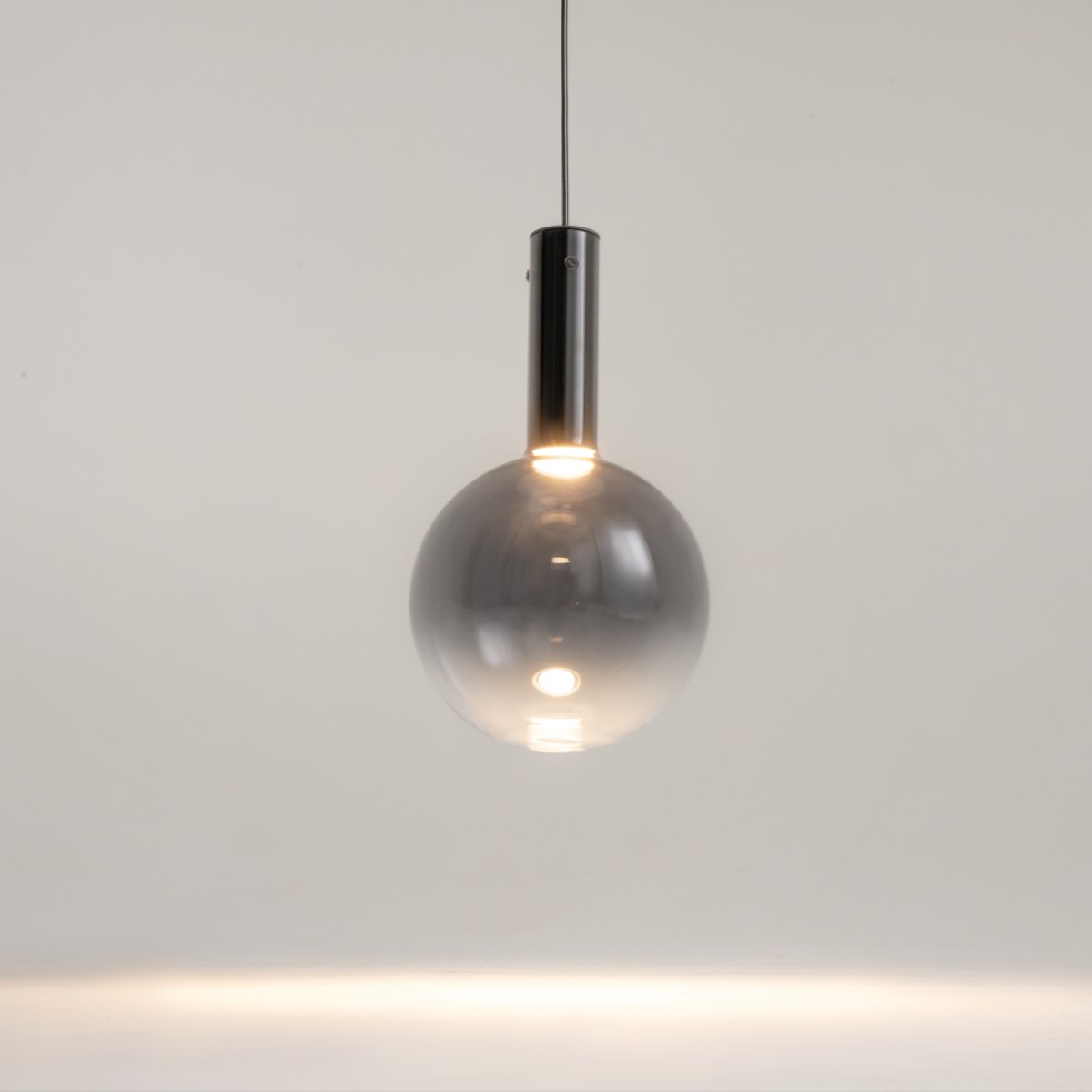Nebula Ø25 Zwart hanglamp Van Maytoni - De blauwe glazen bol, met een verloop van donker aan de bovenkant naar bijna transparant aan de onderkant, geeft een zwevend effect.