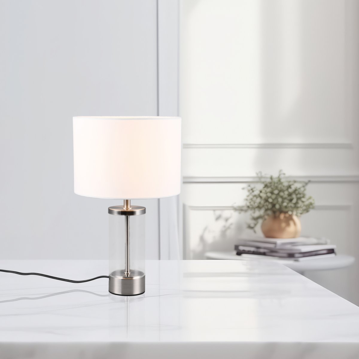 Grazia 34cm Wit tafellamp Van Trio Lighting - De Grazia tafellamp combineert een elegante stoffen kap met een stijlvolle cilindrische voet van glas en metaal, wat een harmonieuze en verfijnde indruk geeft.