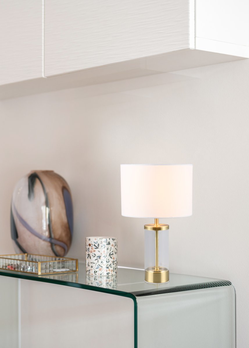Grazia 34cm Mat messing tafellamp Van Trio Lighting - De Grazia tafellamp combineert een elegante stoffen kap met een stijlvolle cilindrische voet van glas en metaal, wat een harmonieuze en verfijnde indruk geeft.