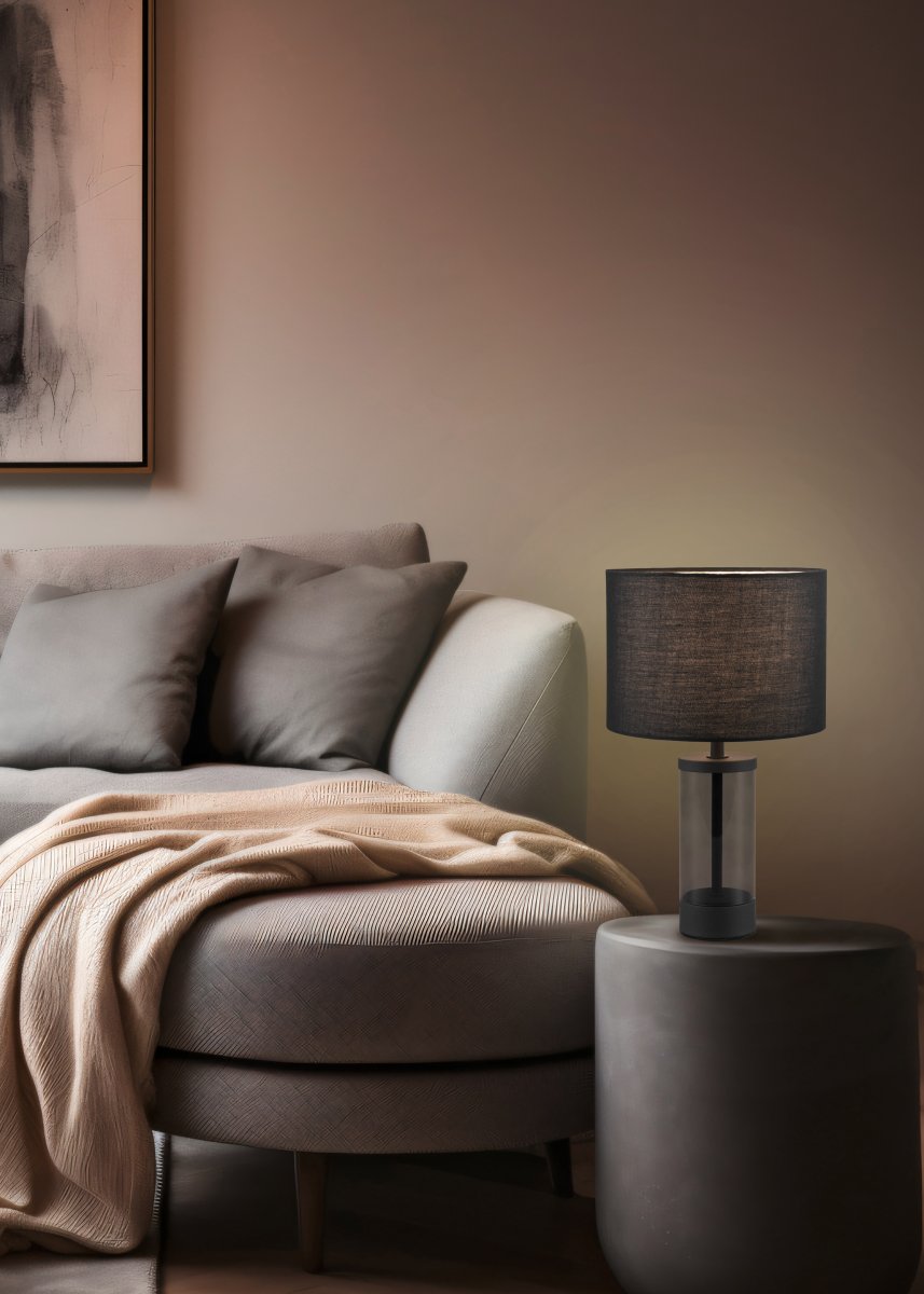 Grazia 34cm Zwart tafellamp Van Trio Lighting - De Grazia tafellamp combineert een elegante stoffen kap met een stijlvolle cilindrische voet van glas en metaal, wat een harmonieuze en verfijnde indruk geeft.